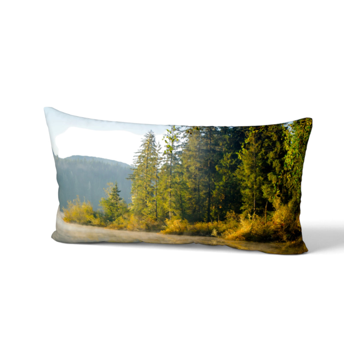 A rectangular lumbar throw pillow featuring a scenic forest landscape print with tall green trees, yellow-brown underbrush, and a pale sky, shown on a white background.