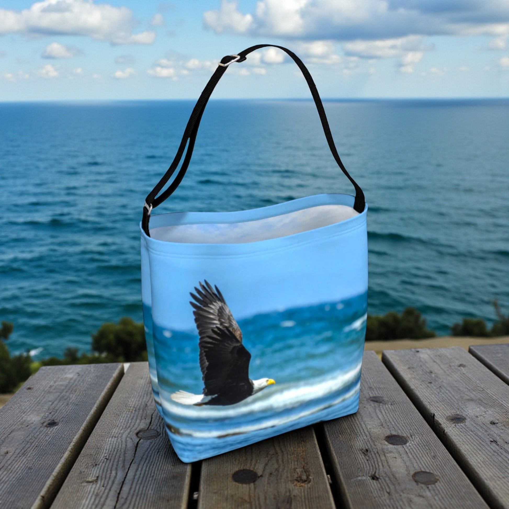 Tote bag with an eagle design on a wooden surface with ocean view