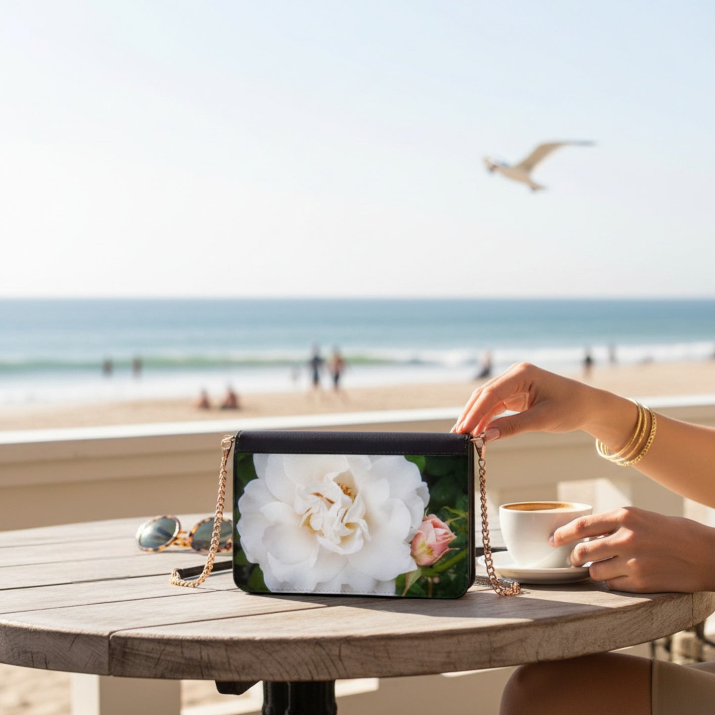 Hand holding a phone case with a floral design on a beach setting