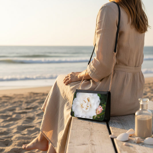 Woman sitting on a beach with a floral handbag