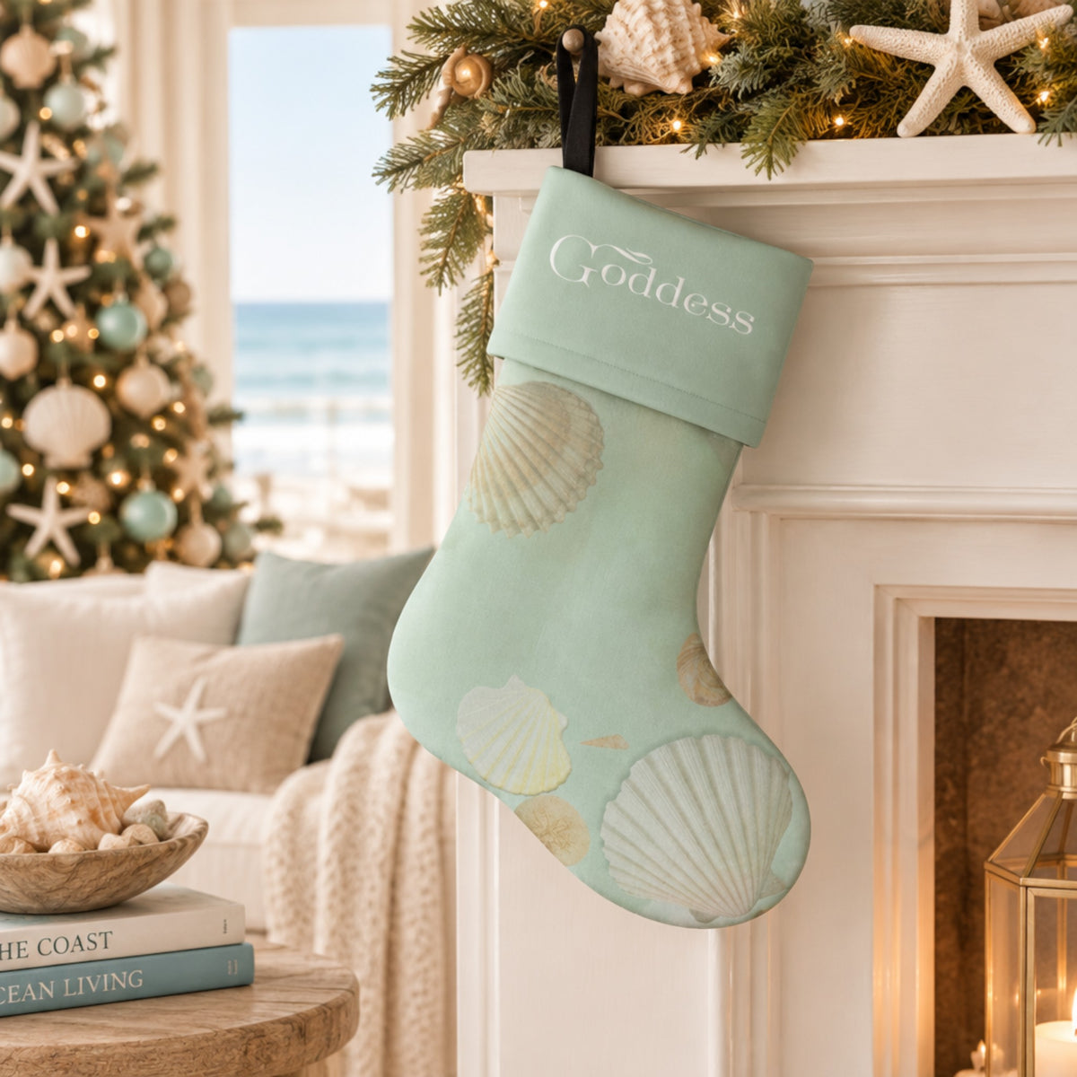 A mint green Christmas stocking with a seashell pattern and the word 'Goddess' printed on the cuff, held by a woman in a cozy living room with a decorated Christmas tree in the background.