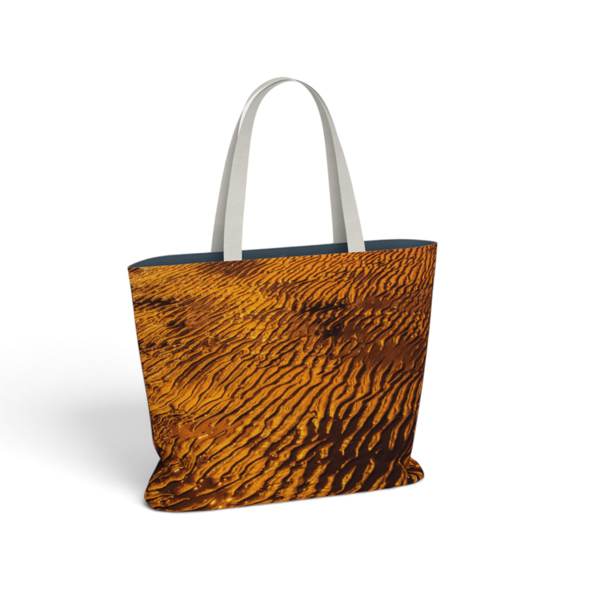 A tote bag featuring a detailed desert dune pattern in golden brown and orange, with contrasting light gray handles, shown on a plain white background.