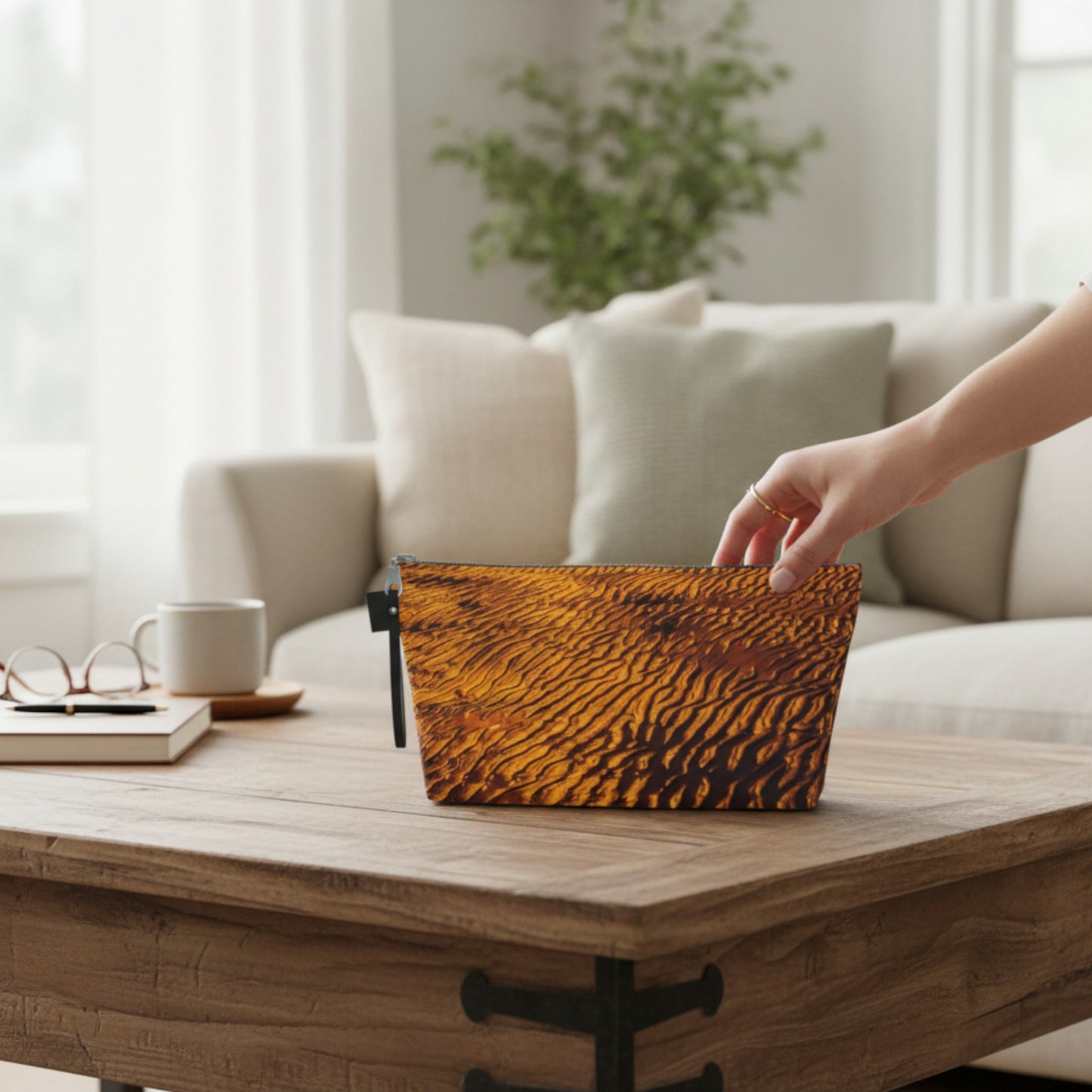 Person placing a sand design pouch on a wooden table in a living room.
