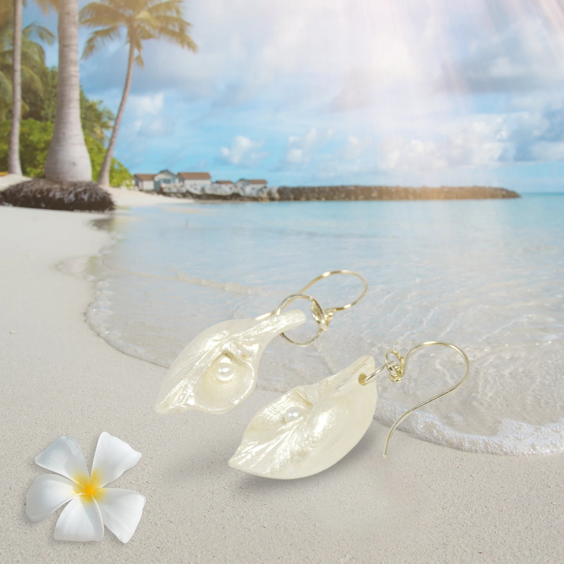 Harmony Earrings made of natural seashells and real freshwater pearls.  The earring are shown on the beach at low tide.
