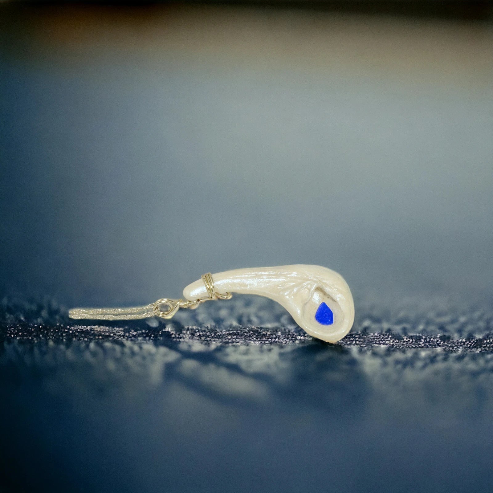 The pendant is shown on its side to give the viewer a different way to see the pendant.  The background is dark blue