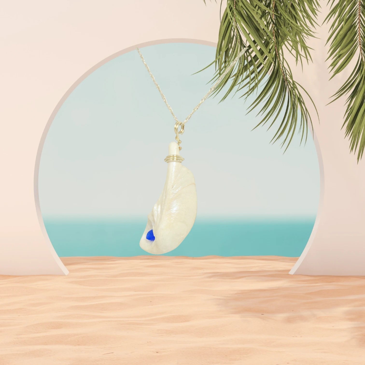The cobalt blue sea glass pendant is shown hanging from a chain with a ocean background.  The pendant is turned to show the left side of the pendant.