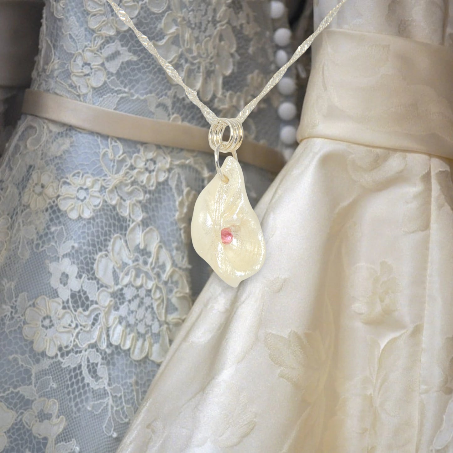 Jewel natural seashell with a real teardrop shaped rose cut pink tourmaline gemstone compliments the pendant. The background shows bridesmaid and wedding dresses.