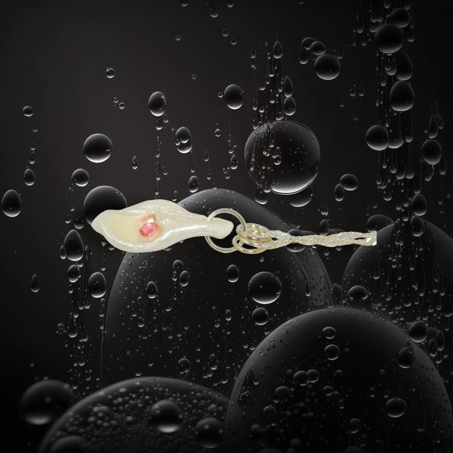Jewel natural seashell with a real teardrop shaped rose cut pink tourmaline gemstone compliments the pendant. The pendant is shown on its side with a black background with water bubbles.