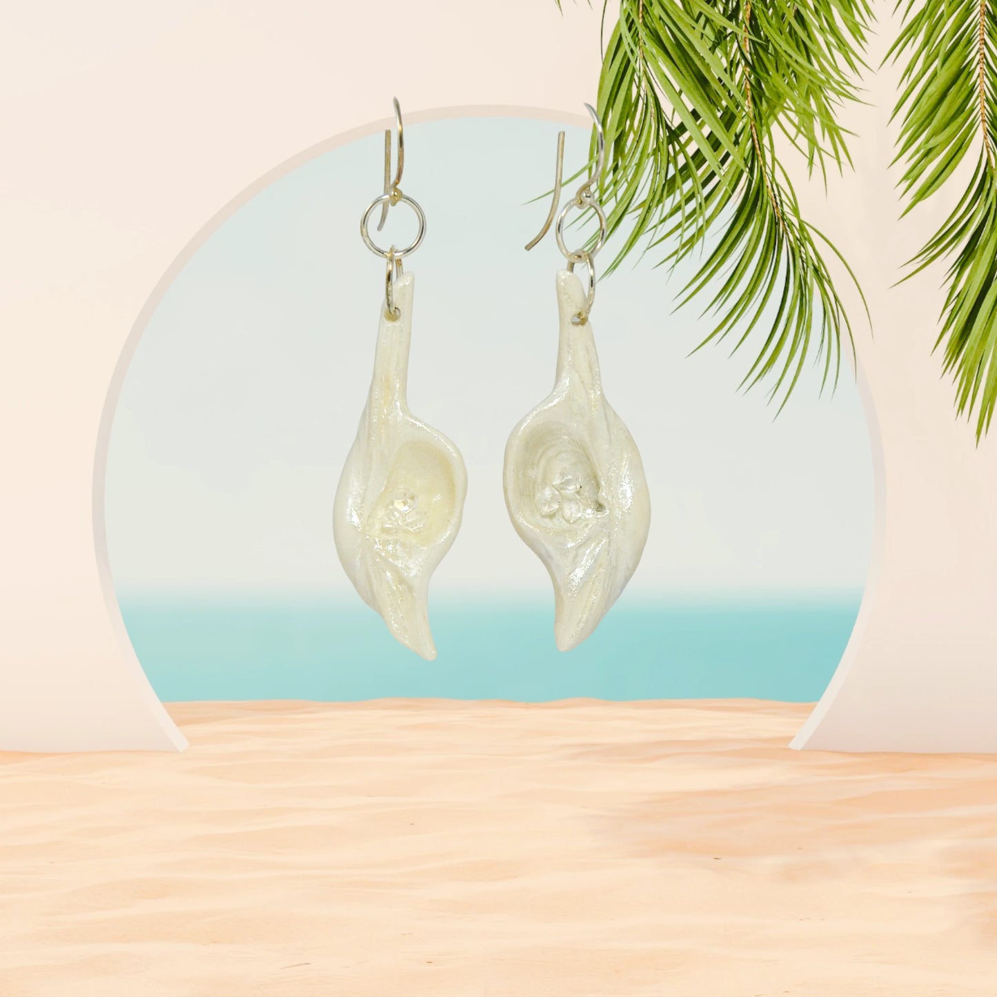 Dream Stone natural seashell earrings with herkimer diamonds. The earring are hanging in a archway looking towards the ocean.