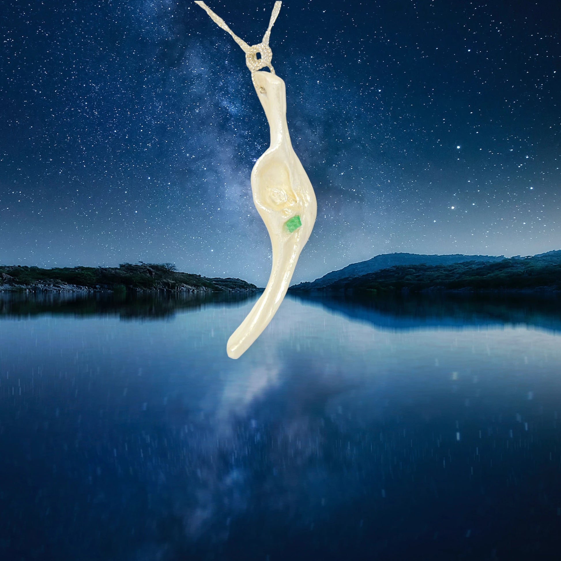 Empress natural seashell pendant with a Herkimer Diamond and Emerald. The pendant is hanging from a chain with a night landscape of water, mountains and starry sky.