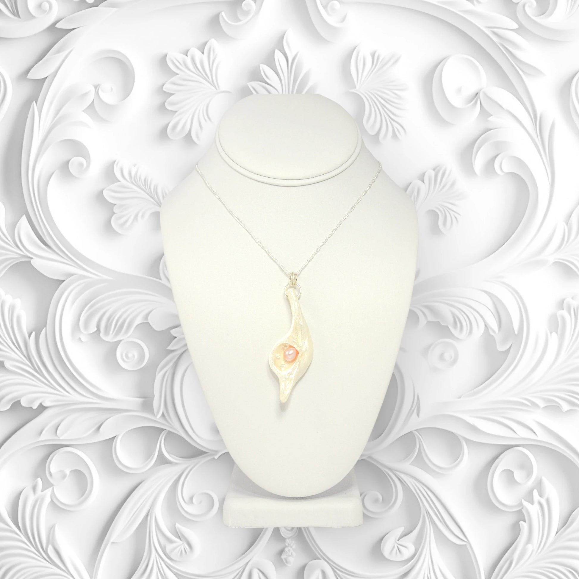 The pendant Champagne on Ice is shown on a necklace displayer.  The pendant is hanging from a chain.  The background is a 3d swirl design in white.