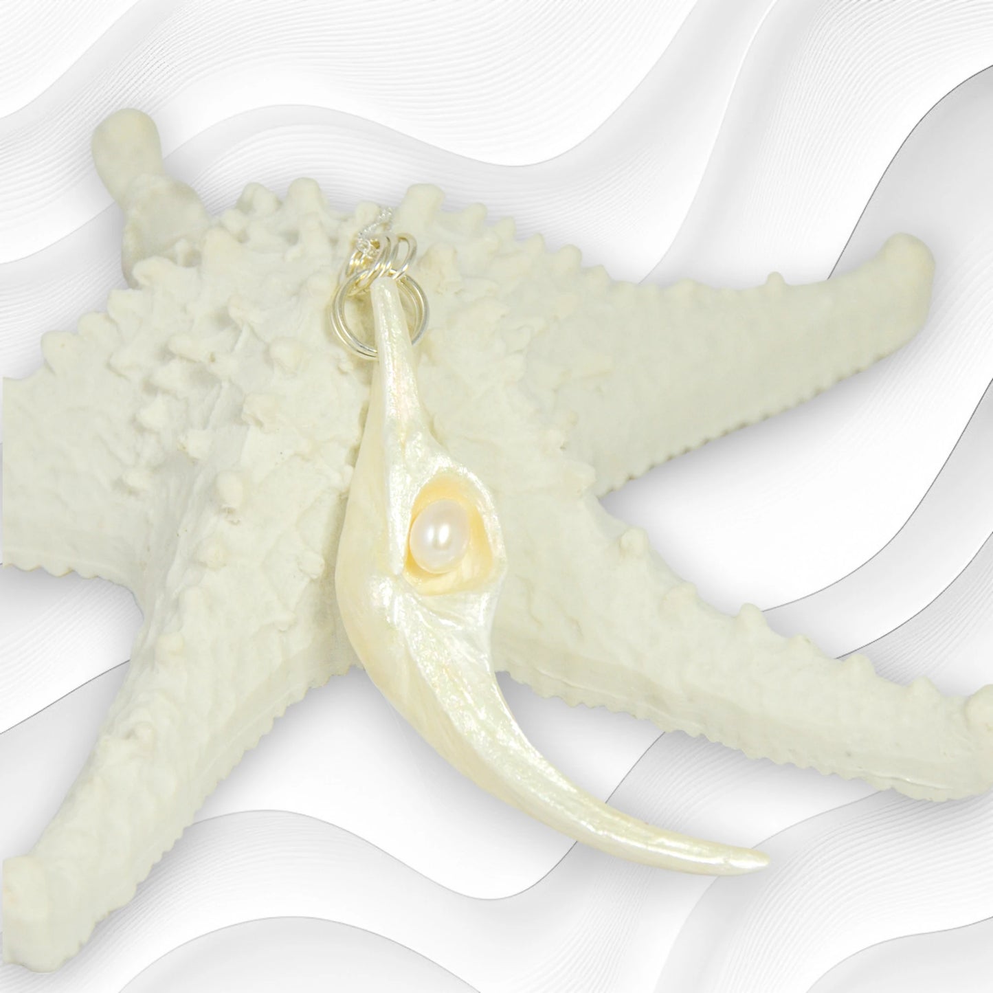 Jupiter is a natural seashell pendant with a real freshwater pearl. The pendant is shown resting on a starfish with a white background.