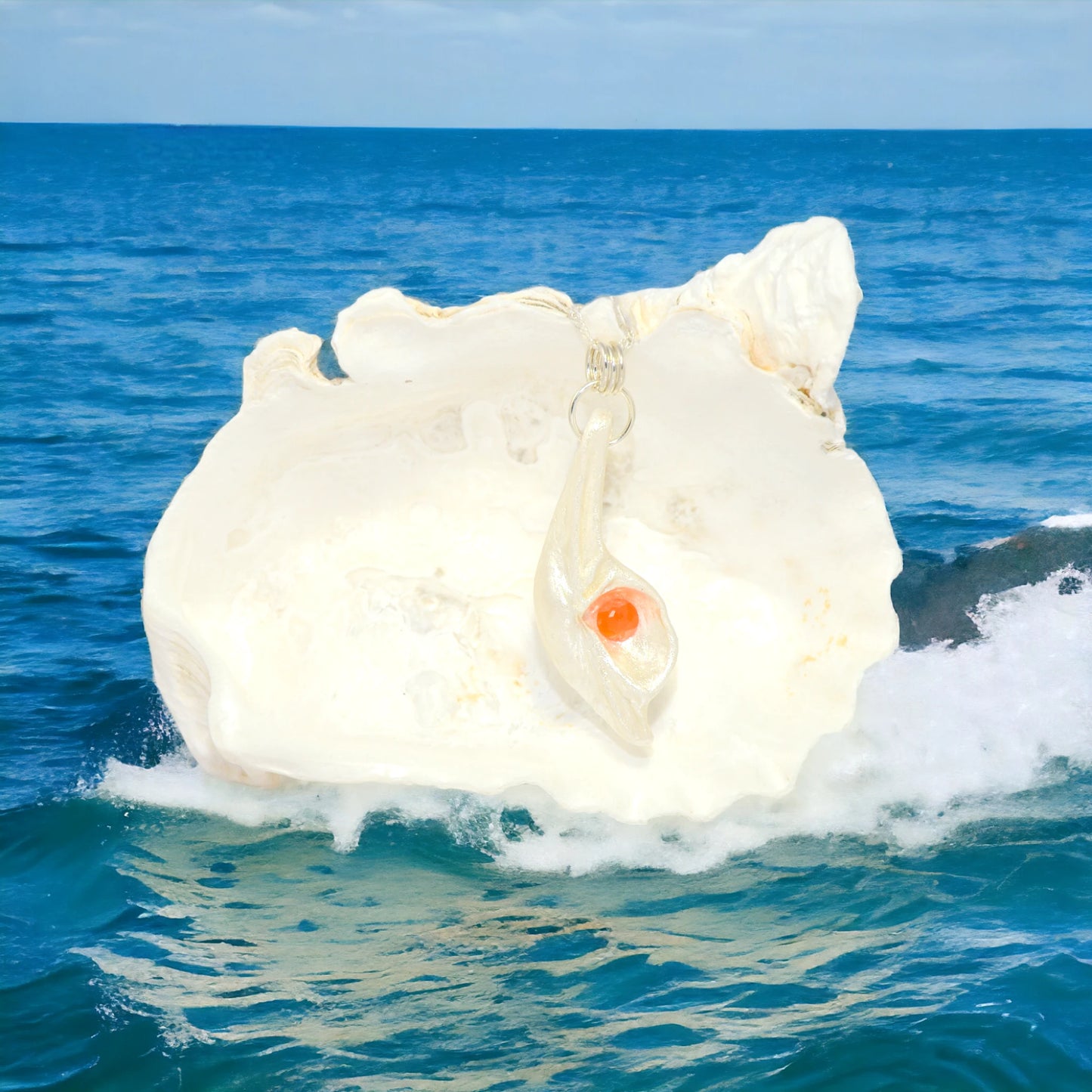 Natural Seashell pendant, elevating the beautiful natural nuances to new heights. The pendant is perfectly adorned with a mesmerizing rose cut Carnelian gemstone. The pendant is hanging in front of a larger seashell in the ocean.