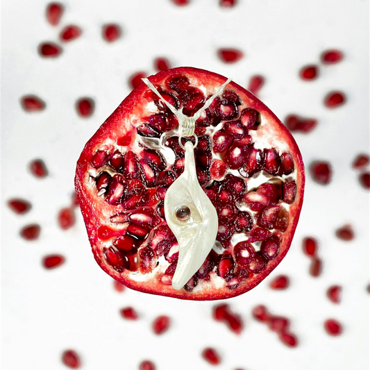 Pomegranate natural seashell pendant is adorned with a stunning Garnet gemstone. The background is of a half pomegranate.