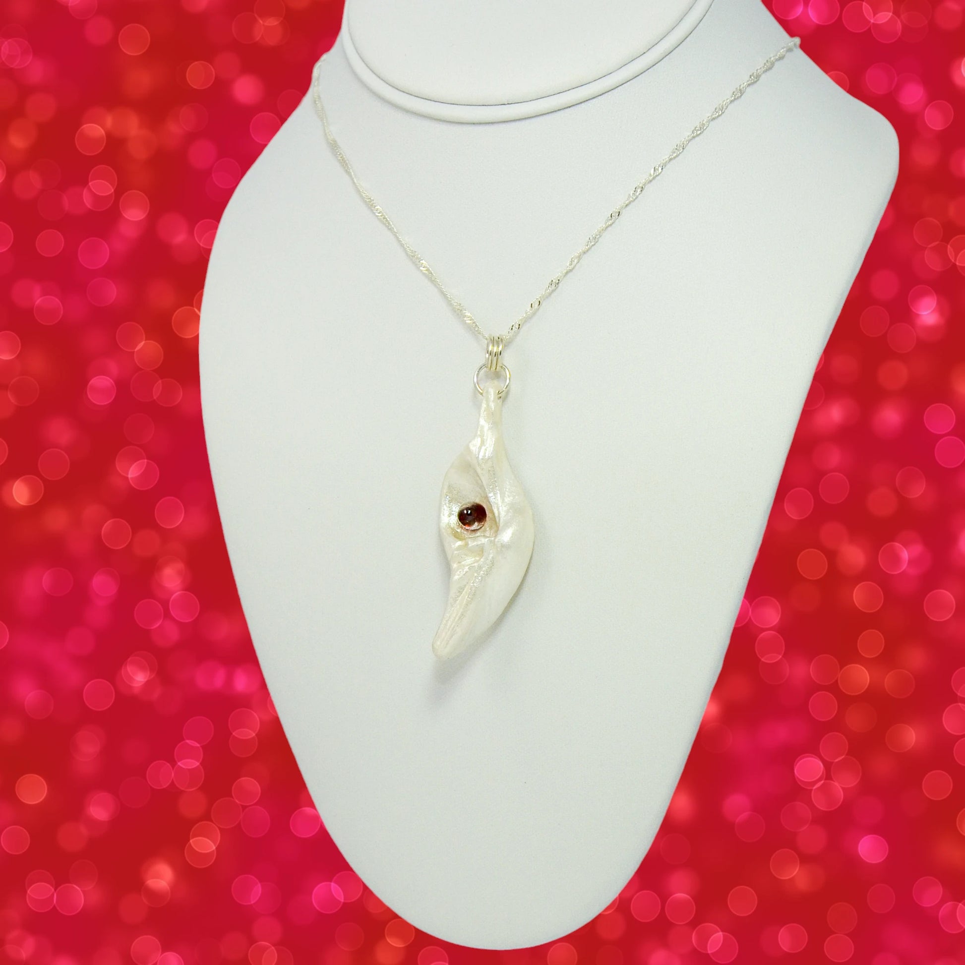 Pomegranate natural seashell pendant is adorned with a stunning Garnet gemstone. The pendant is turned so the viewer can see the left side of the pendant.