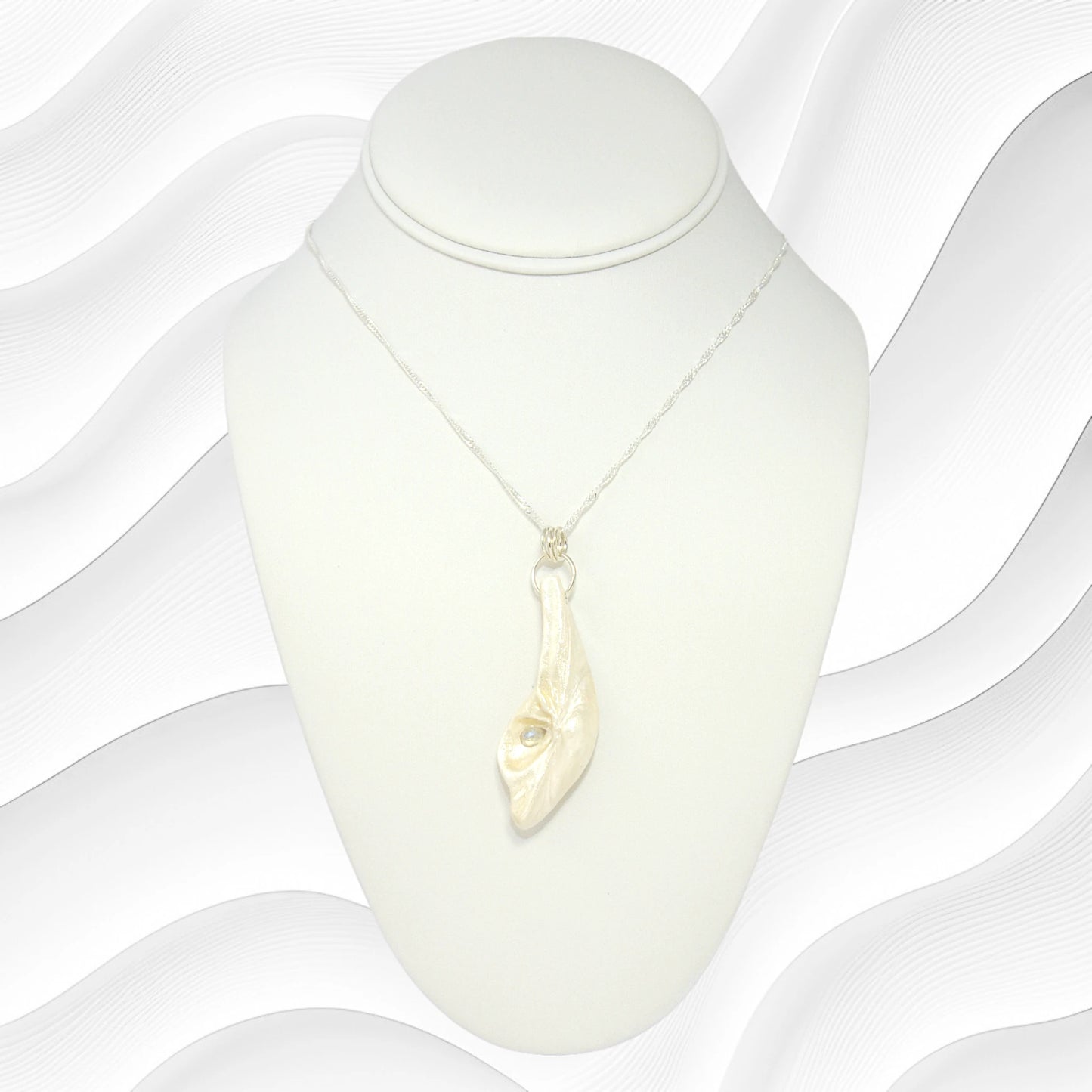 Cool Summer pendant made of natural seashell with a tear drop shape rose cut labradorite gemstone. The pendant is shown on a white necklace displayer hanging from a necklace.  The background is white wavy lines.