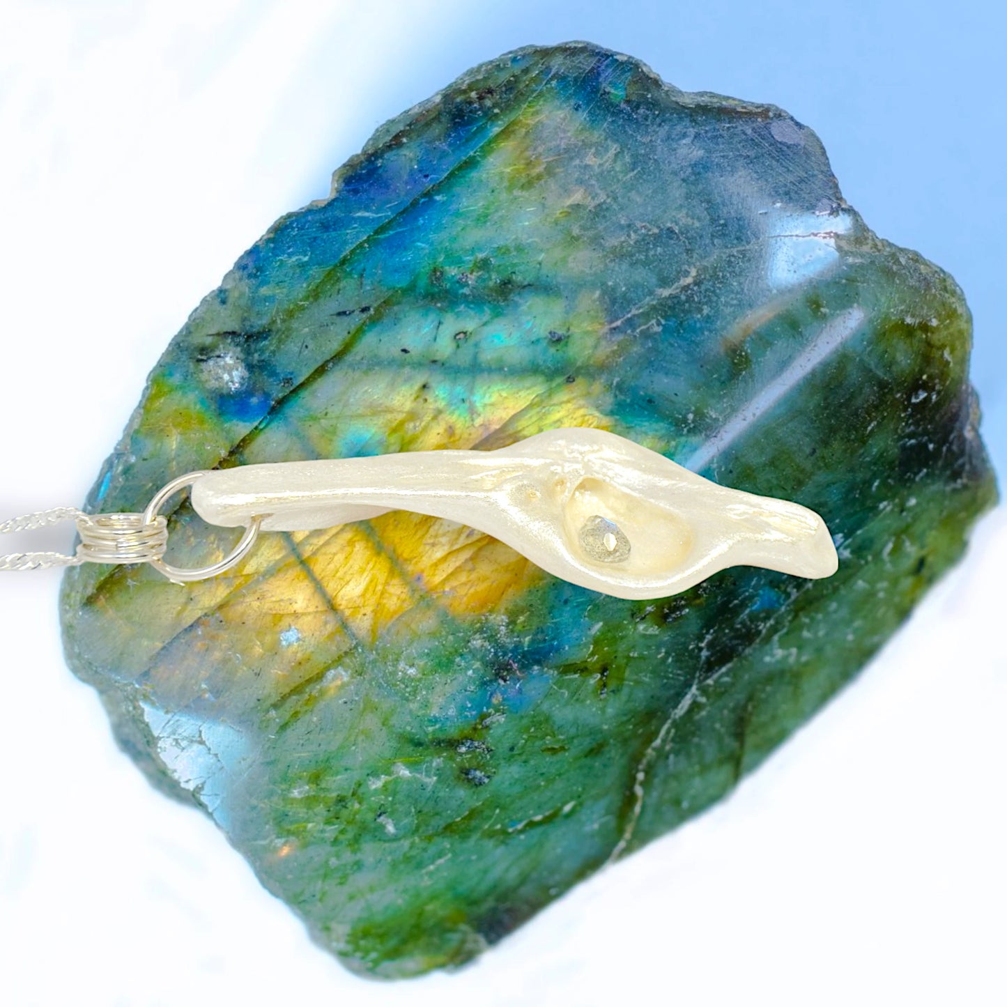 This video of Cool Summer pendant made of natural seashell with a tear drop shape rose cut labradorite gemstone.  The pendant is shown resting on a large piece of labradorite.