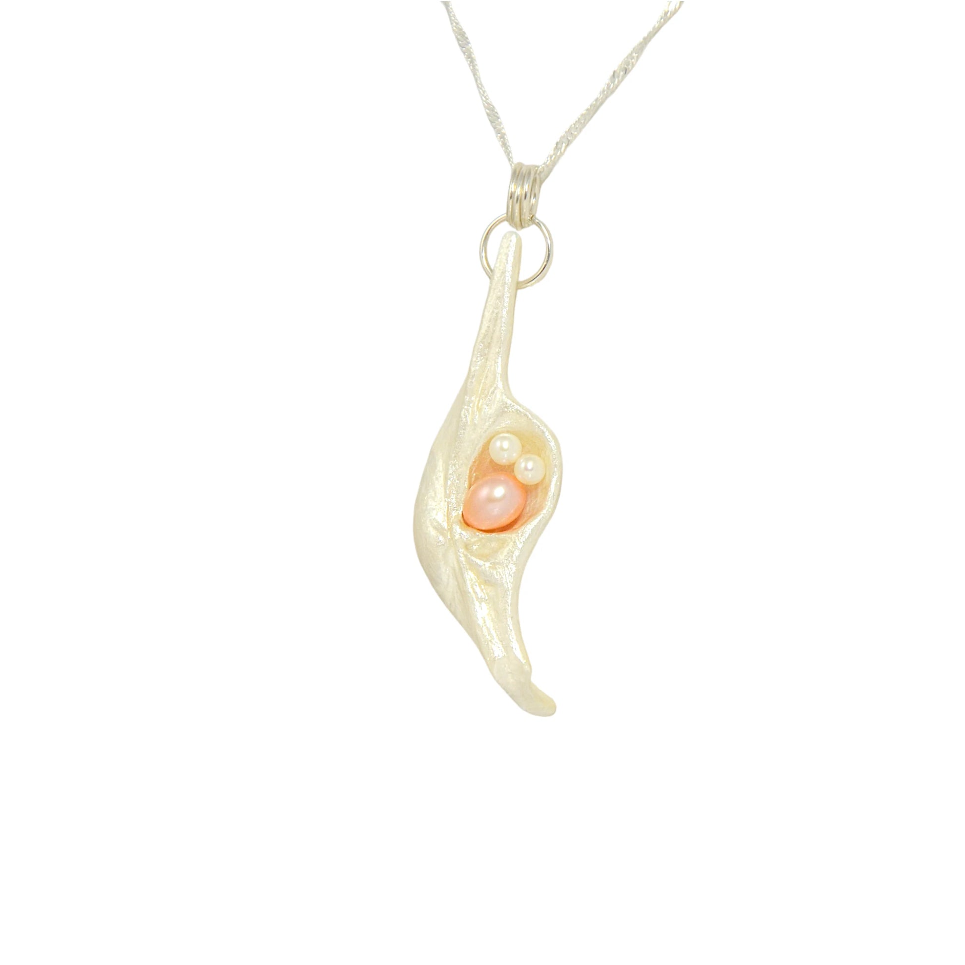 This natural seashell pendant has a real 7-8mm pink freshwater pearl and two baby pearls. The pendant is turned so the viewer can see the left side of the pendant.
