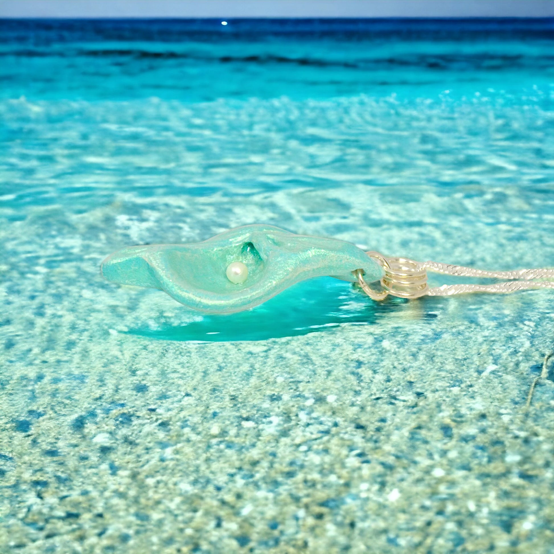 Ocean Pearl natural seashell pendant has a  real freshwater baby pearl. The pendant is laying in ocean water at low tide.