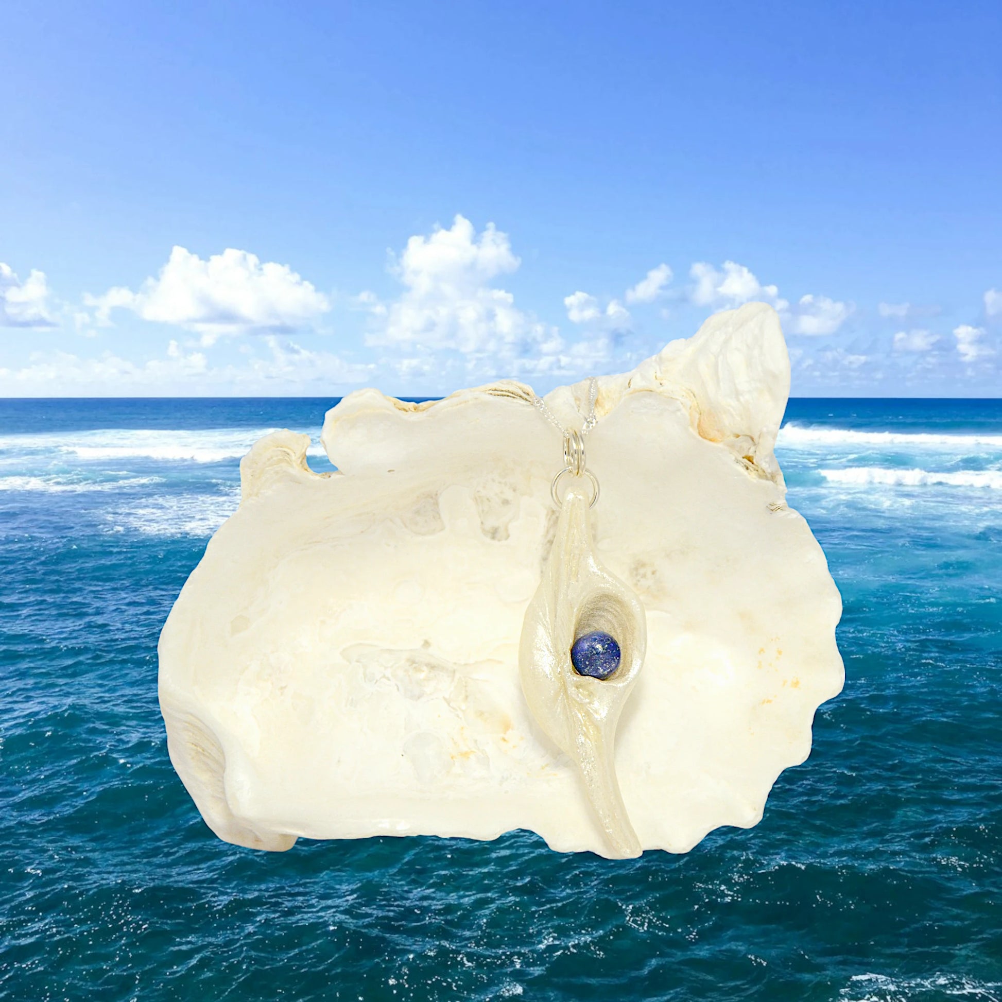 Vision is a natural seashell pendant with a Lapis Lazuli gemstone.  The ocean waves are in the background.