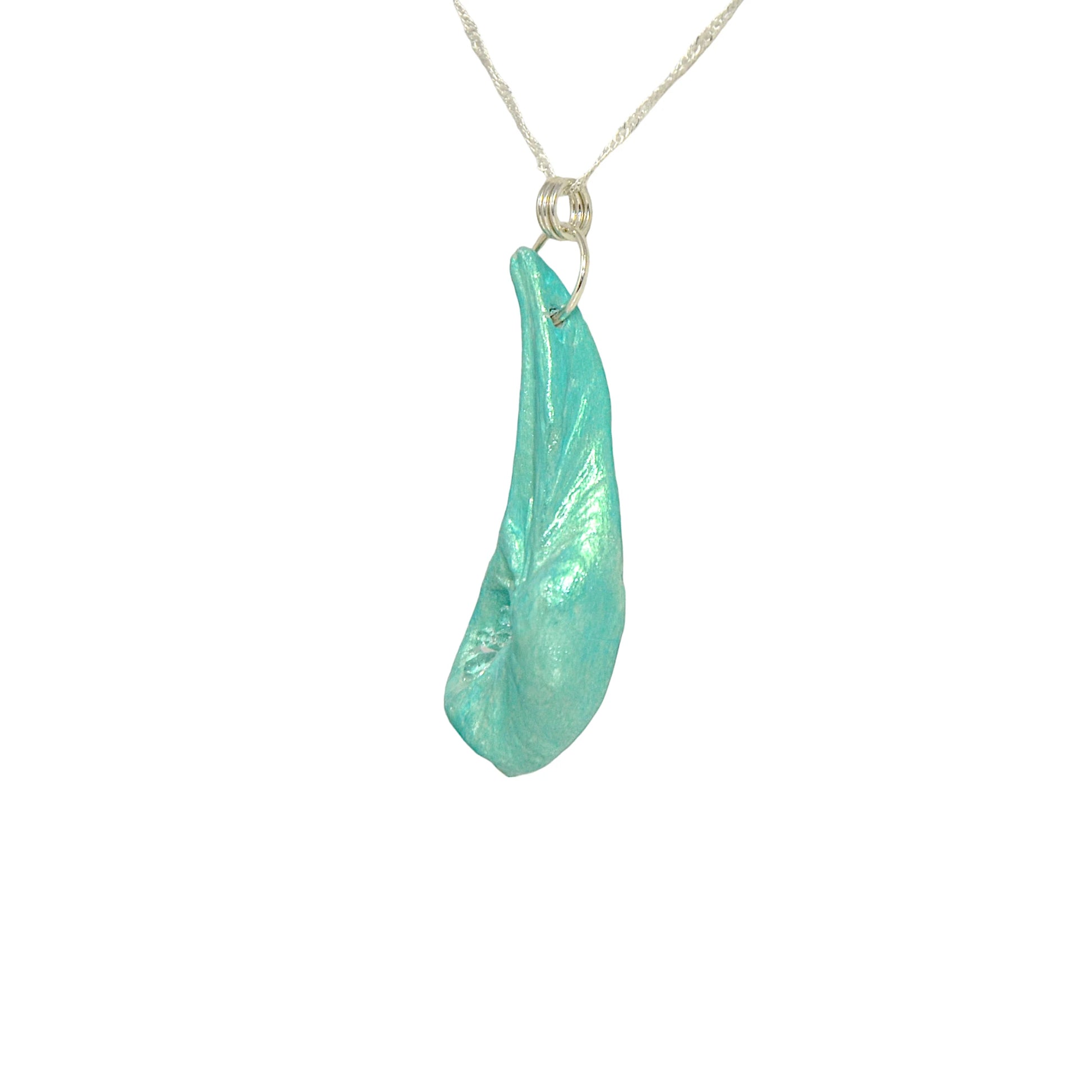 The Cascadia Pendant created with a natural seashell from the beaches of Vancouver Island.  The seashell is turquoise and has high quality herkimer diamonds. is shown turned to show the left side of the pendant.