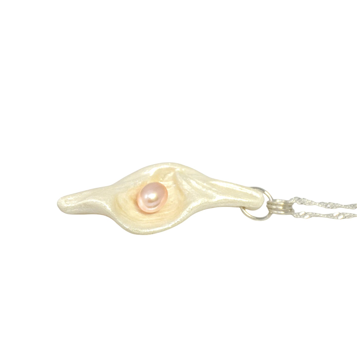 Glow natural seashell pendant with a pink freshwater pearl. The pendant is laying on a tabletop.