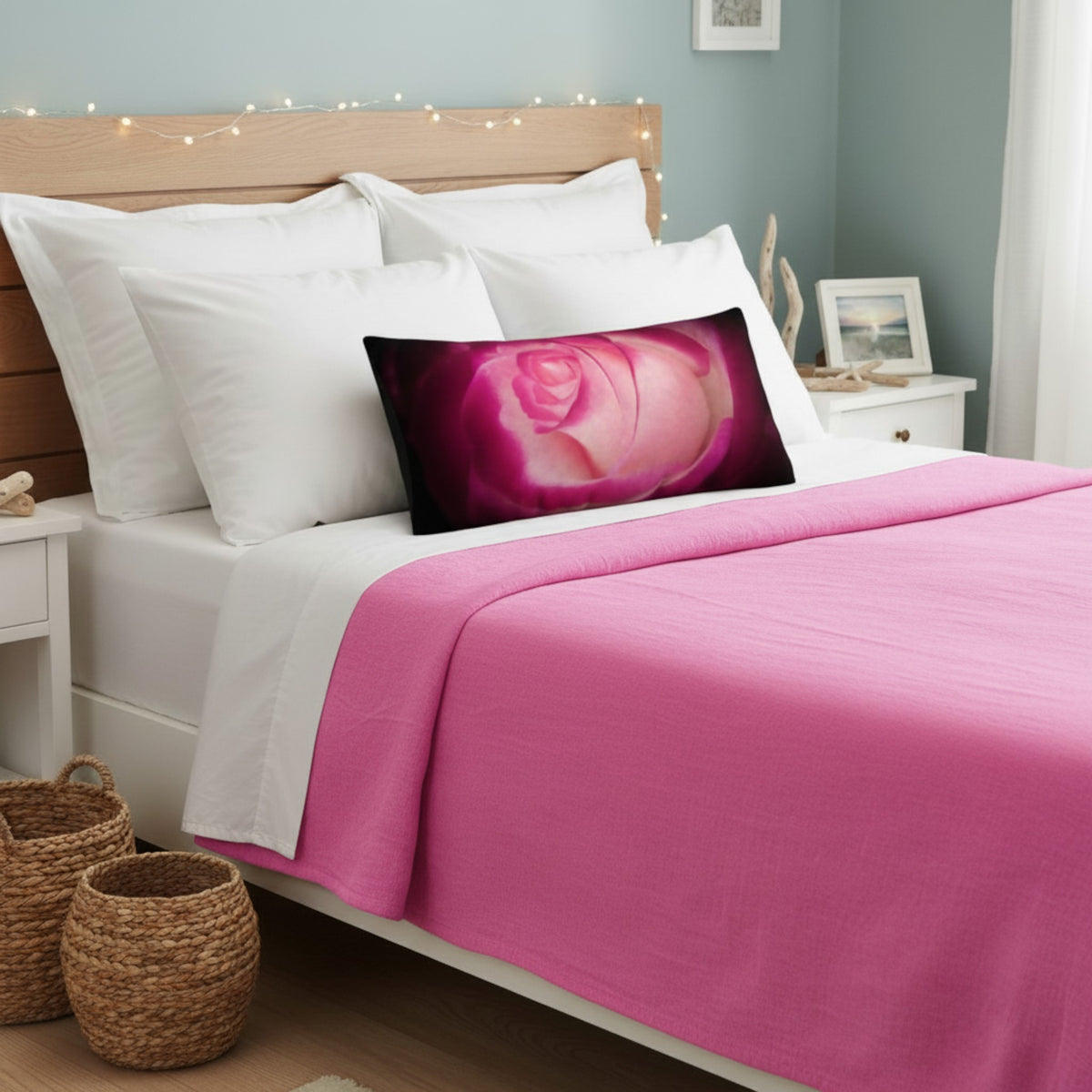 Rose pillow on a bed with a pink blanket.