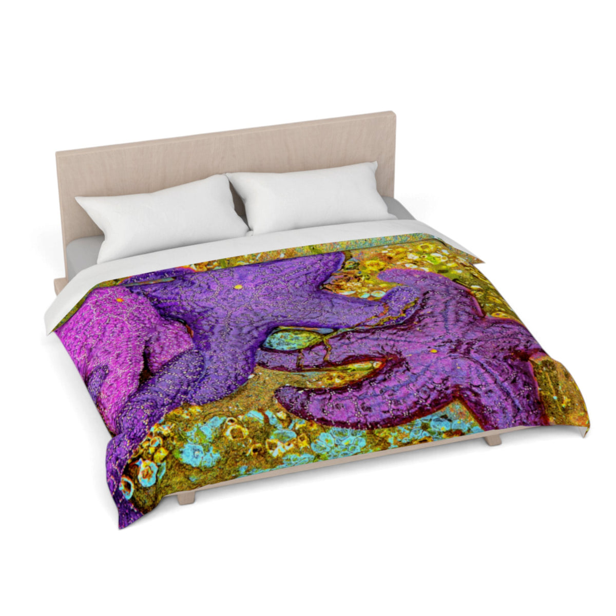 A bed dressed with a colorful duvet cover featuring a large purple starfish design over a gold and turquoise background, shown on a light wood bed frame with white pillows against a white studio background.