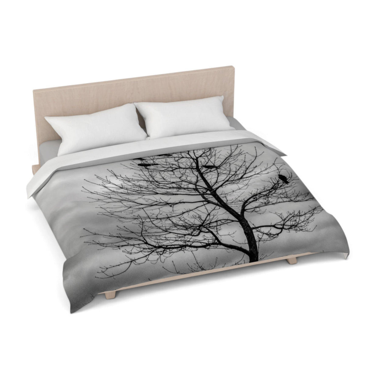 A bed dressed in a duvet cover featuring a black-and-white tree branch pattern, shown on a light wood bed frame against a plain white background.