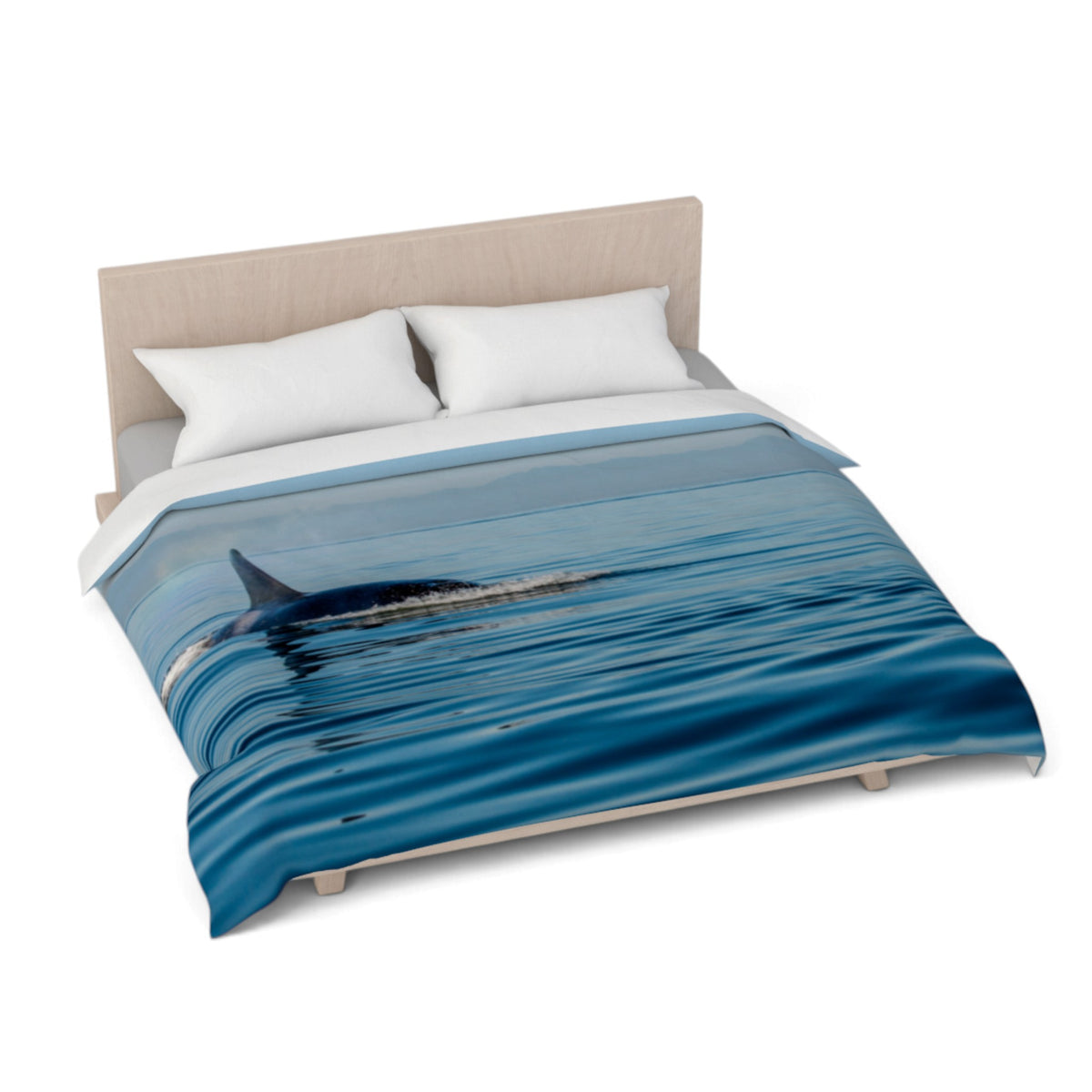 A bed dressed with a duvet cover featuring a blue ocean and dolphin print, styled with two white pillows and a light wood headboard against a white background.