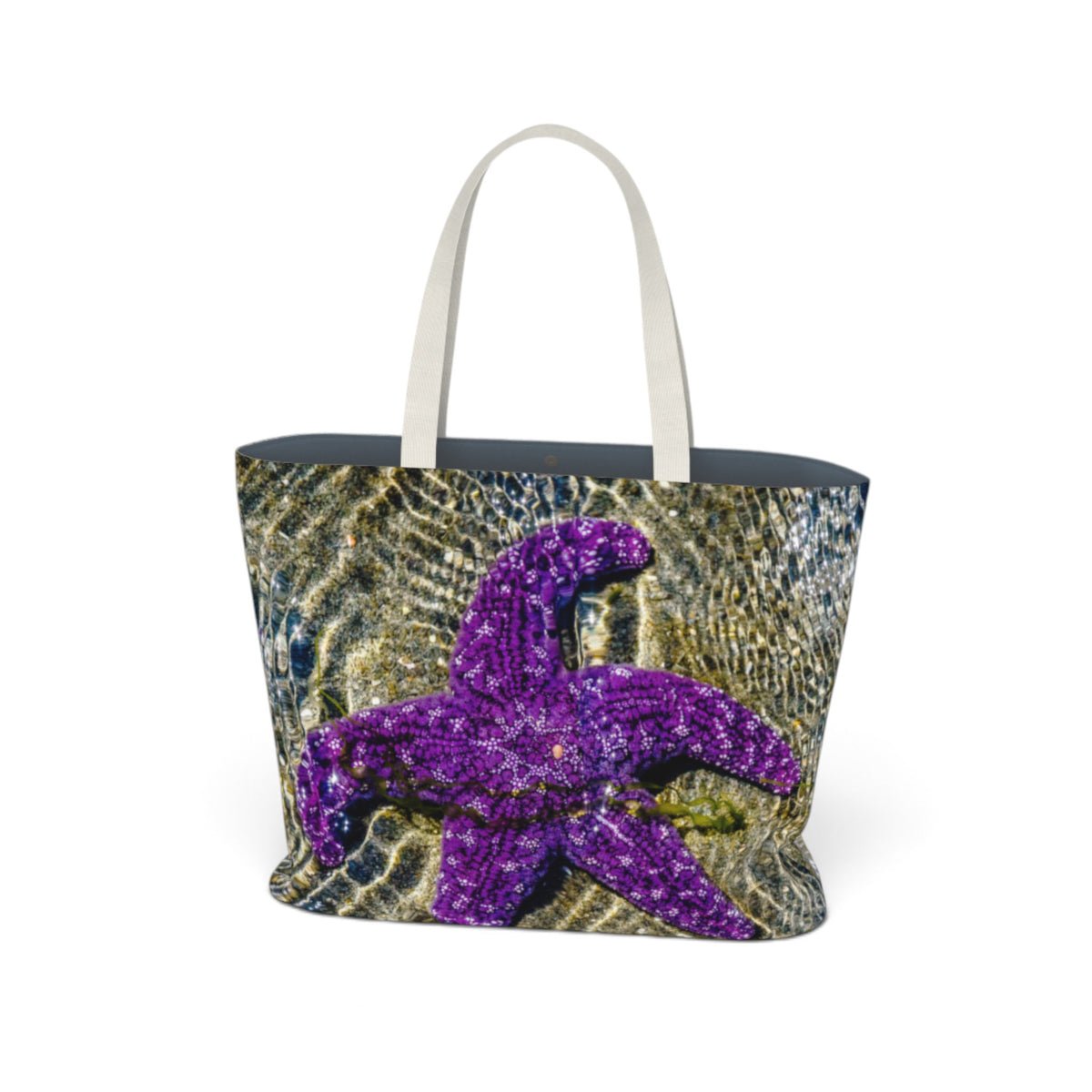 A tote bag featuring a purple starfish design over a gold and blue sunlit water texture print, with white shoulder straps, shown on a plain white background.