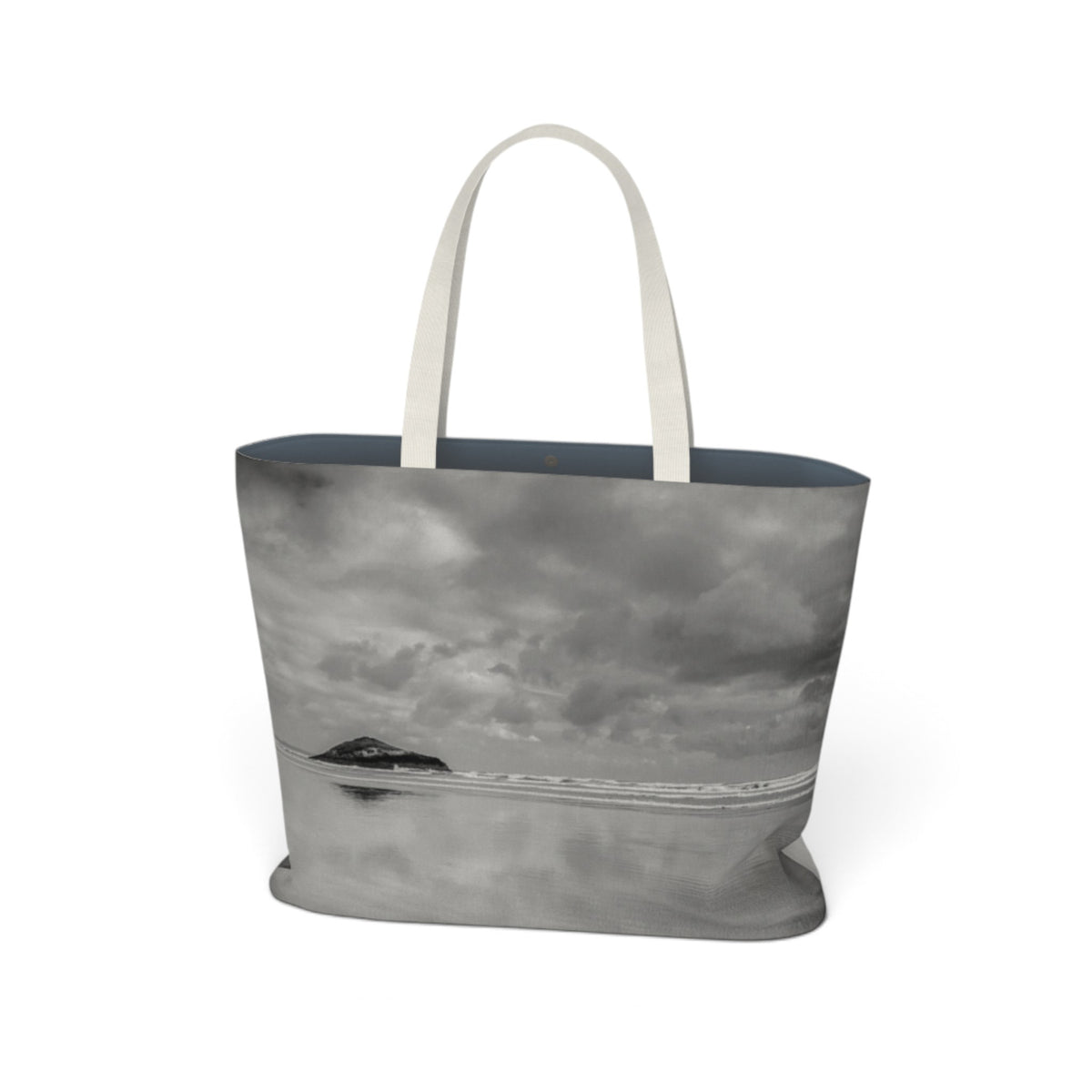 A tote bag featuring a black and white landscape photograph of a lake and island under a cloudy sky, with light beige fabric handles, shown on a plain white background.