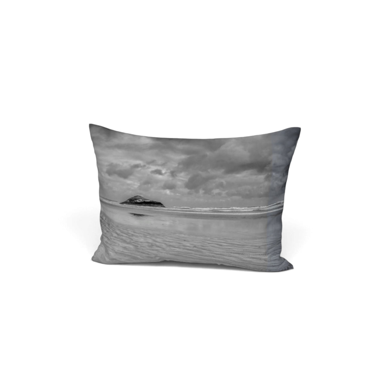 A rectangular throw pillow featuring a black and white landscape photograph of a beach, ocean, and cloudy sky, shown against a plain white background.