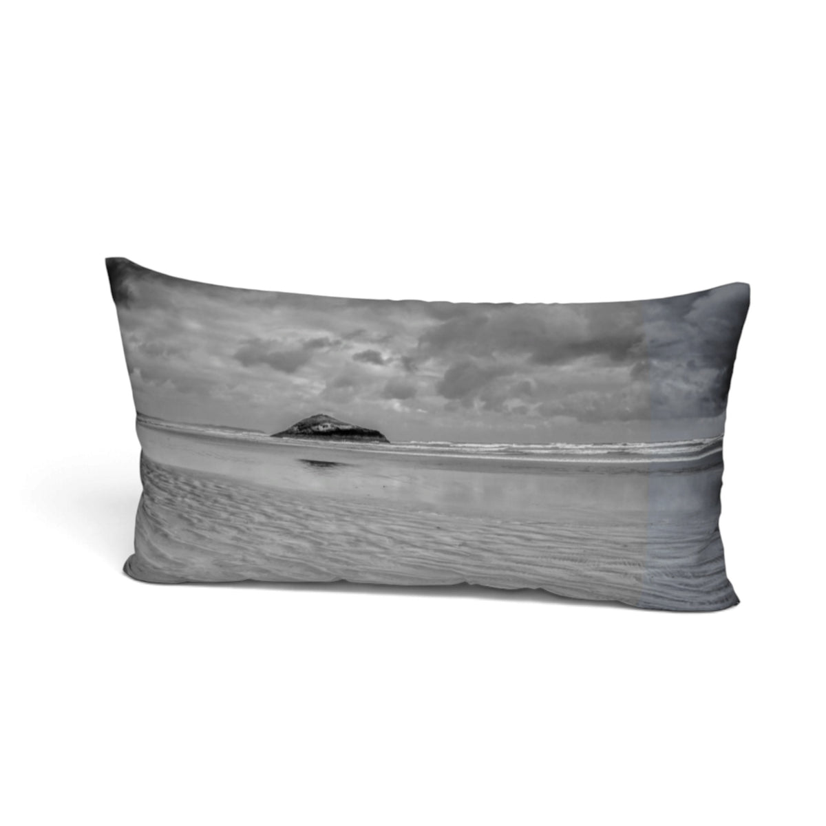 A rectangular lumbar pillow featuring a black and white landscape photograph of a beach with a small island under a cloudy sky, shown on a plain white background.