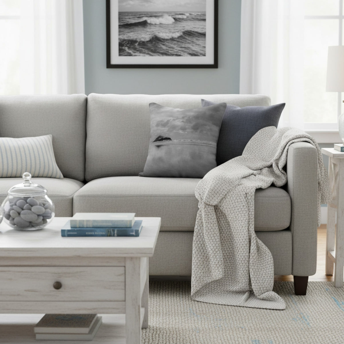 Beach theme pillow on a gray sofa in a living room.