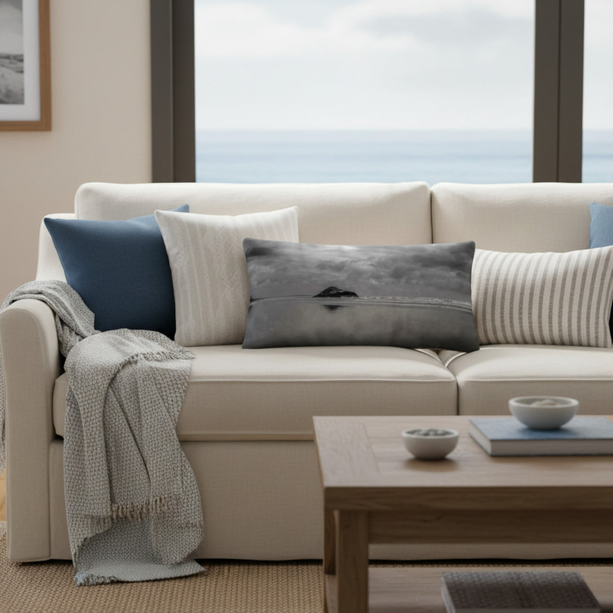 A throw pillow with a printed image of a coastal scene, featuring a pillow cover with a grayish-blue hue and a visible island in the distance.