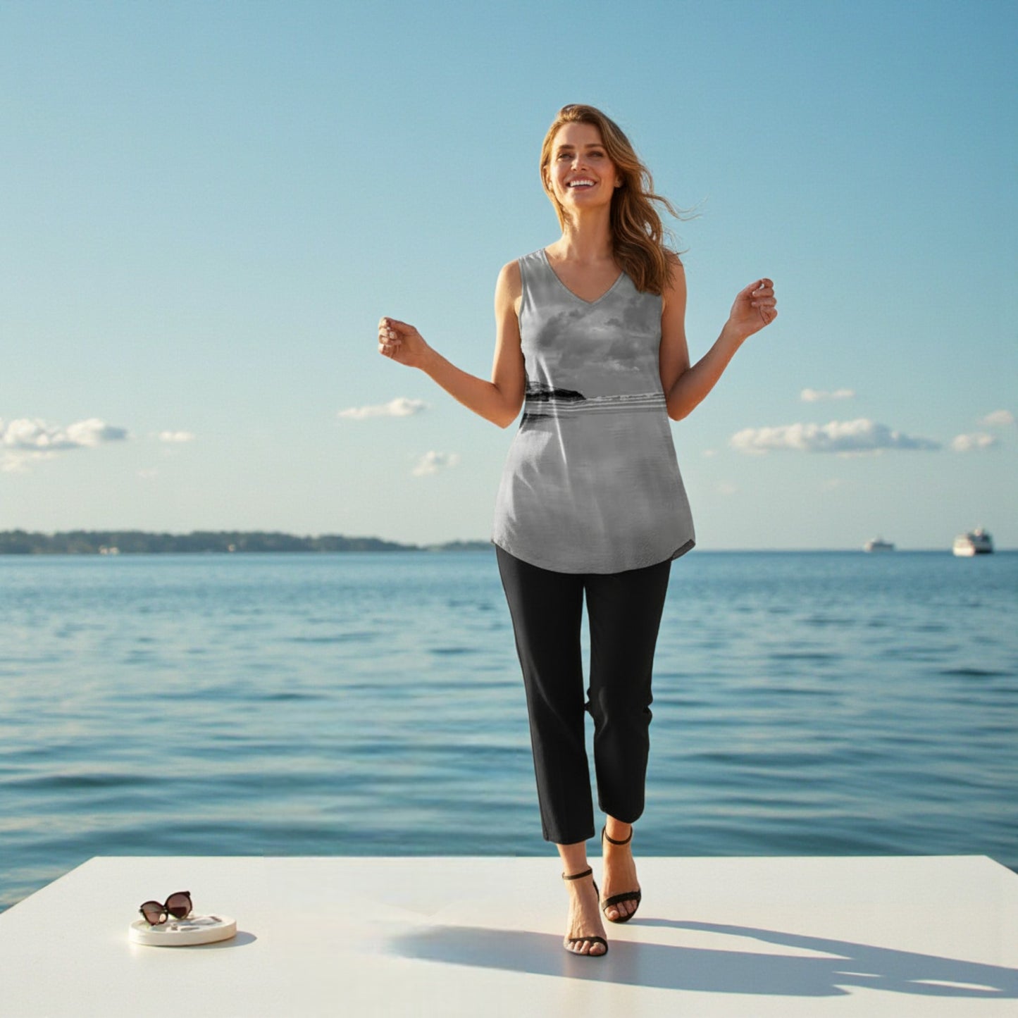 Woman standing on a dock by the water with a clear blue sky.