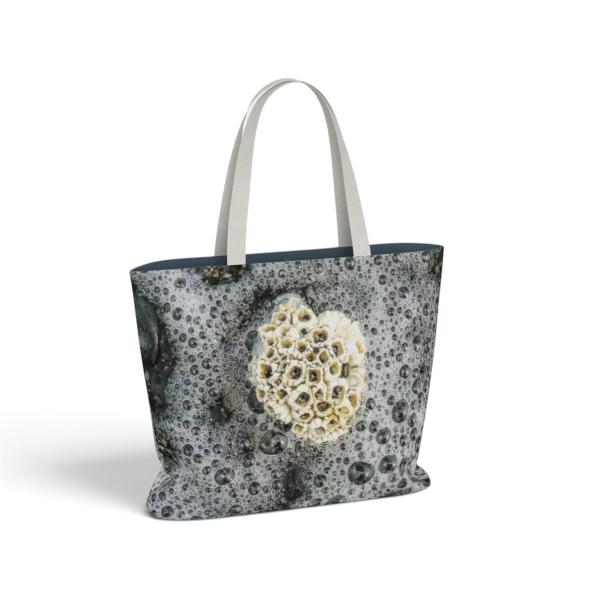 A tote bag featuring a photographic print of barnacles on wet, bubbly seawater, with light beige shoulder straps, shown against a plain white background.