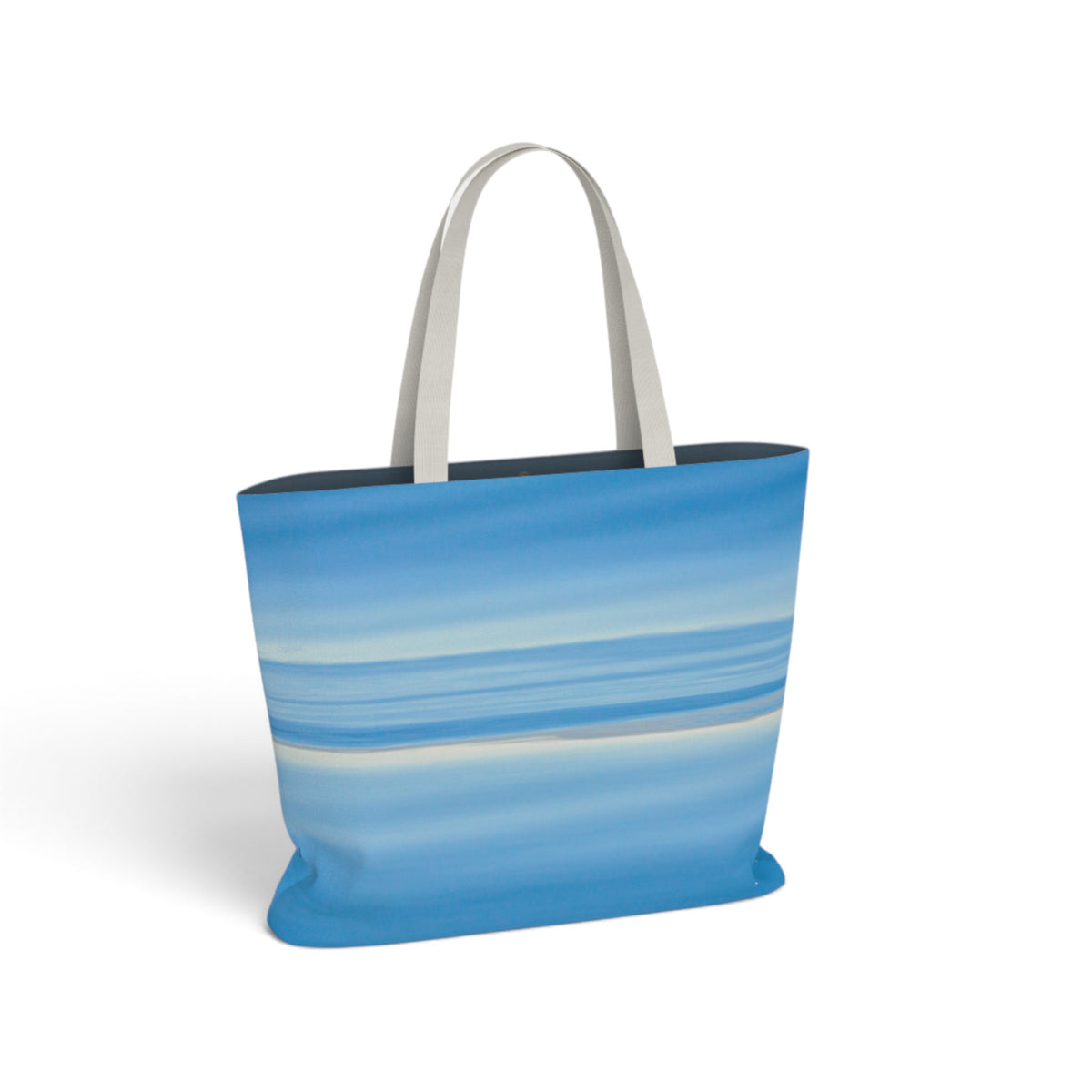 A tote bag featuring an abstract blue and white horizontal wave-like pattern, with light gray handles, shown on a plain white background.