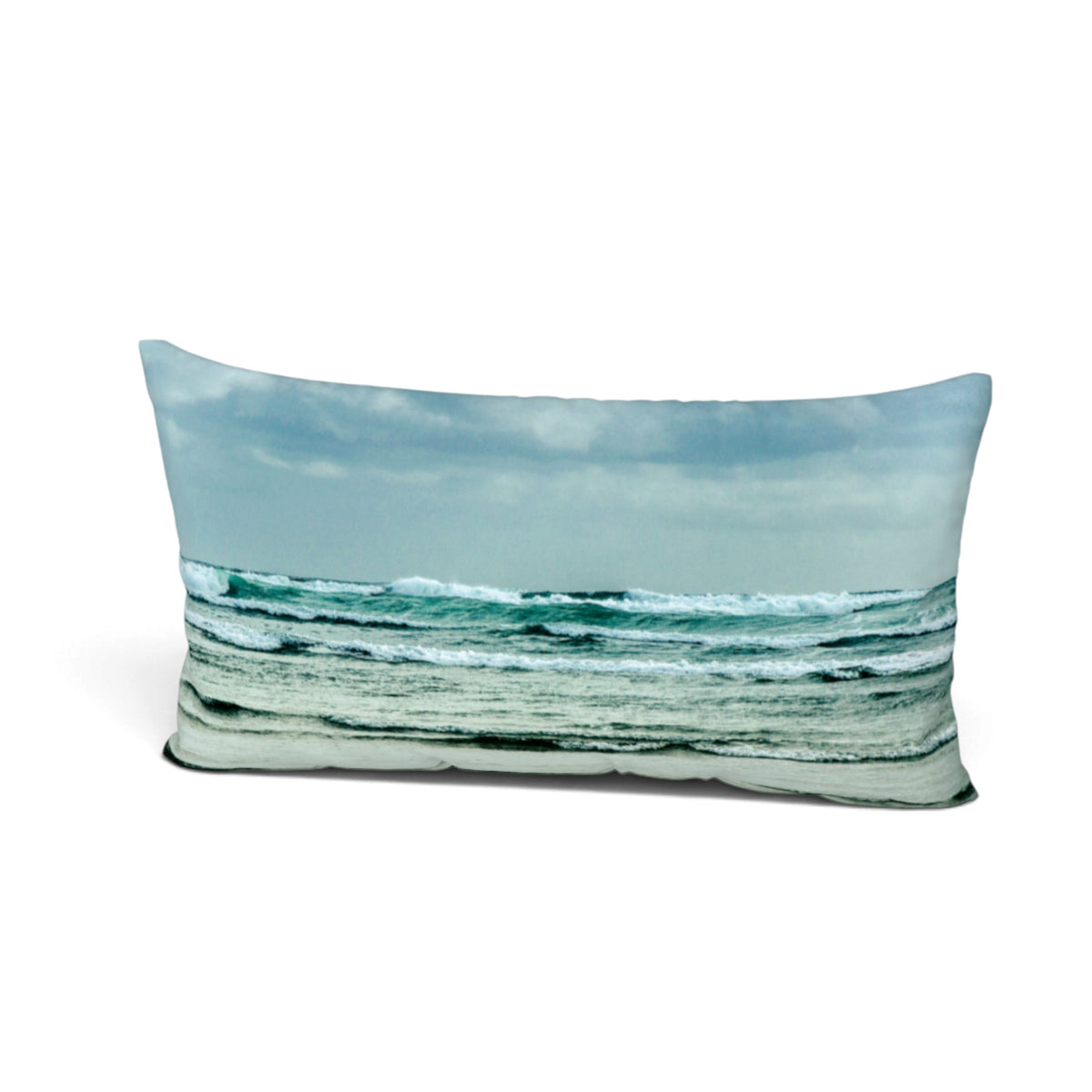 A rectangular throw pillow featuring a photographic print of ocean waves under a cloudy sky, shown against a plain white background.
