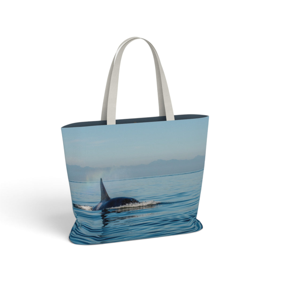 A tote bag with white shoulder straps, featuring a photographic print of an orca whale in blue ocean waters under a pale sky.