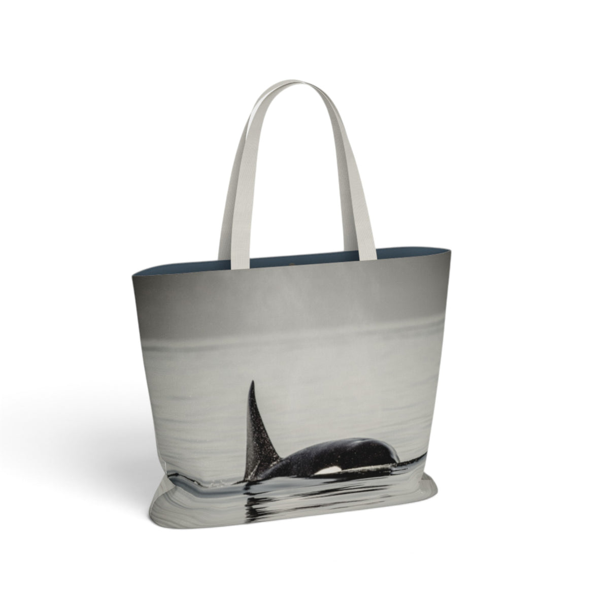 A tote bag with a photographic print of an orca whale fin in water, featuring light gray fabric handles and a dark navy blue inner lining, shown on a plain white background.