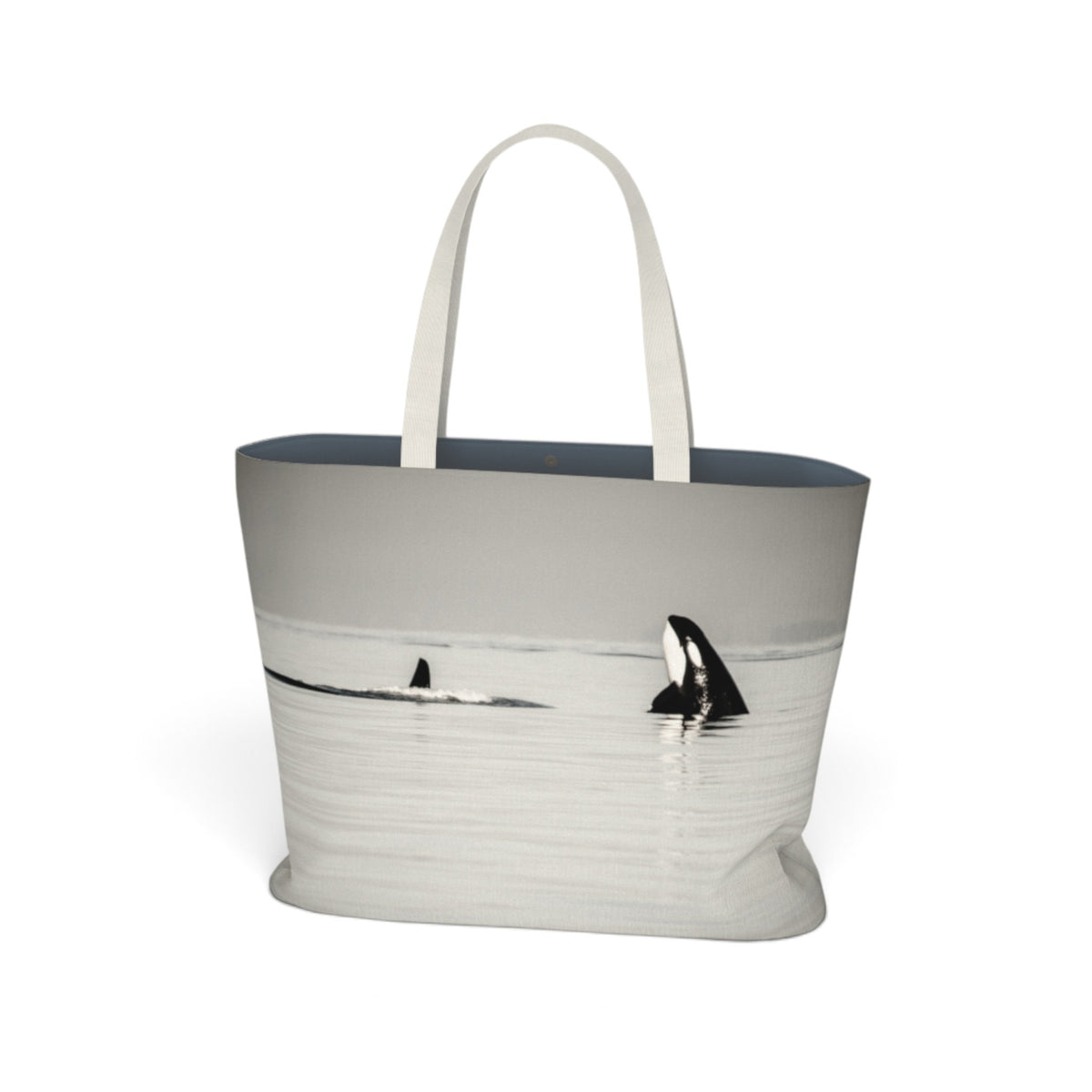 A tote bag featuring a grayscale photographic print of killer whales in the water, with white fabric shoulder straps, shown on a plain white background.