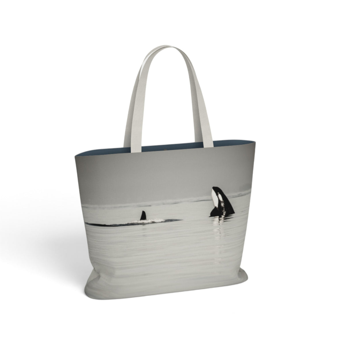 A tote bag featuring a grayscale photographic print of killer whales in water, with light gray handles and a dark navy blue interior lining, shown on a plain white background.