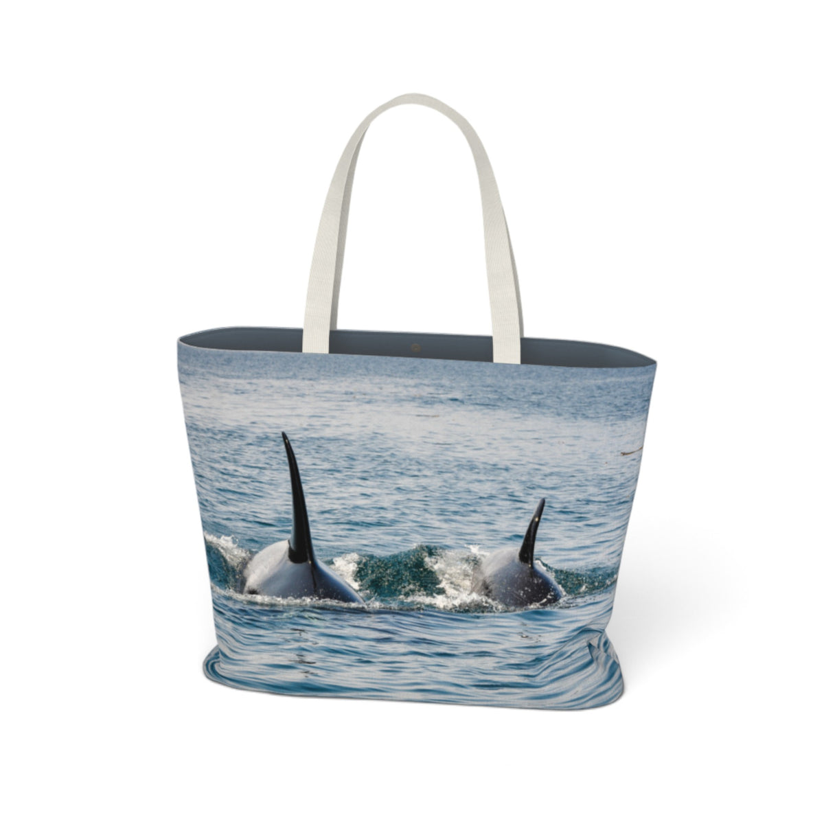 A tote bag with white handles, featuring a photographic print of two orcas surfacing in blue ocean water. The bag is shown against a plain white background.