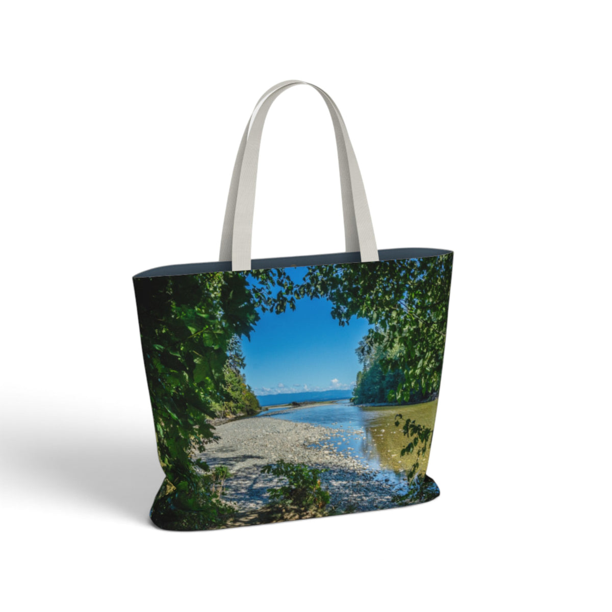 A tote bag featuring a scenic landscape print of a beach, water, and lush green trees, with light gray fabric shoulder straps, shown on a plain white background.