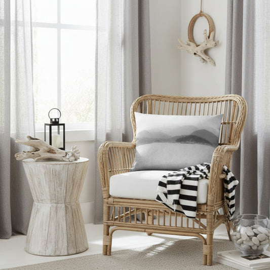 A natural wicker armchair with a white cushion and a black-and-white striped throw blanket, styled in a bright, modern room next to a rustic side table.