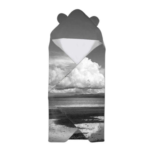 Hooded blanket with a landscape design of a beach and clouds on a white background