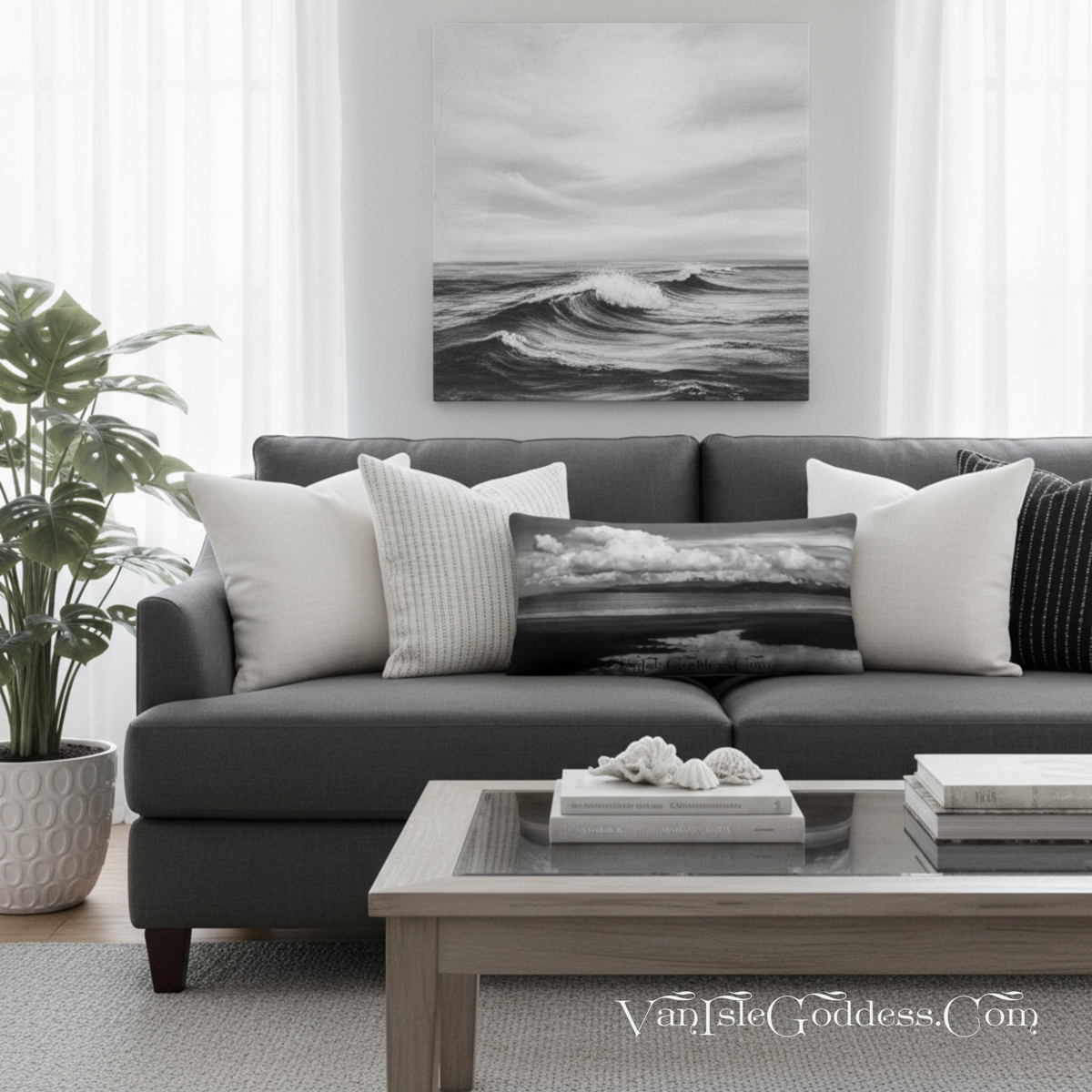 A black and white ocean wave canvas print hangs on a white wall above a modern gray sofa with decorative throw pillows in a bright, contemporary living room.