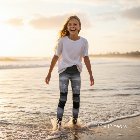 Young girl playing in the water at the beach with a sunset in the background